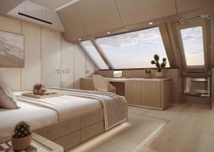 Widok wnętrza luksusowej kabiny Sunreef Yachts z drewnianymi wykończeniami, dużym oknem, łóżkiem oraz miejscem do siedzenia z stołem i roślinami kaktusowymi.