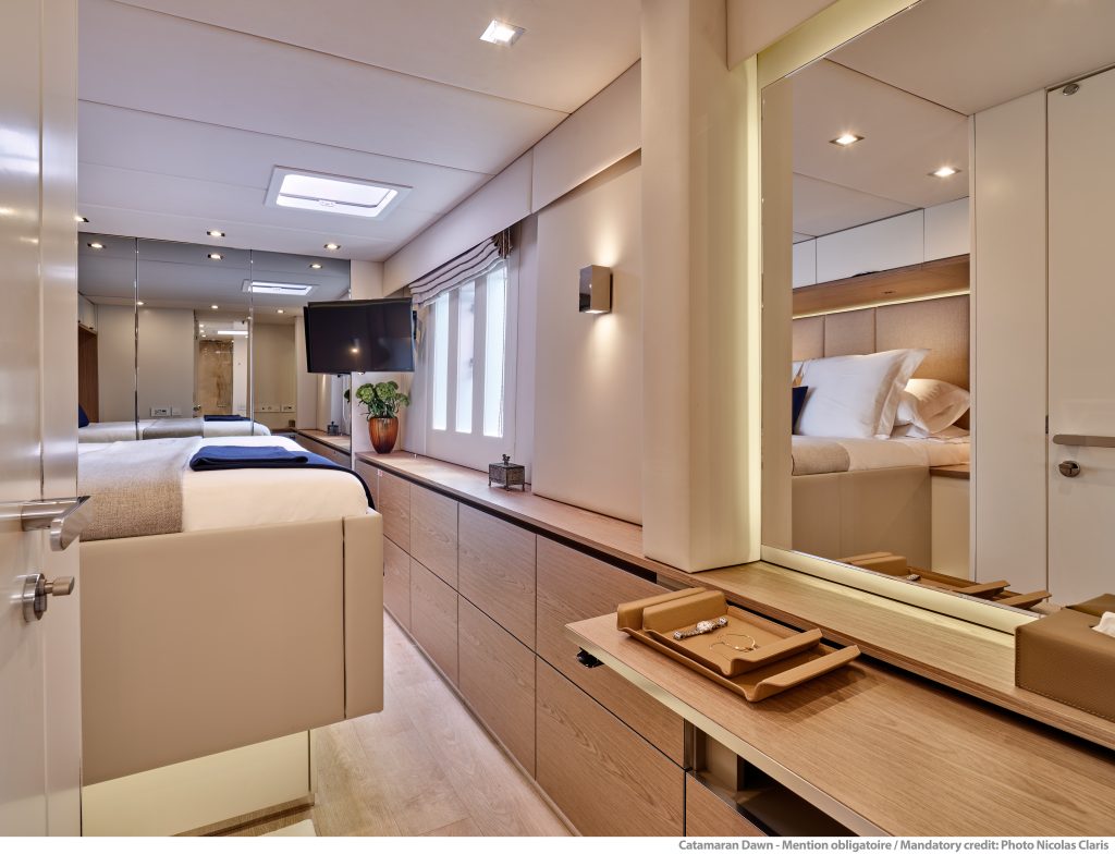 Wnętrze luksusowej kabiny na katamaranie Sunreef Yachts, z wygodnym łóżkiem, eleganckimi meblami i telewizorem.