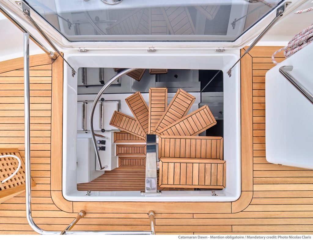 Widok z góry na luksusowy pokład katamaranu Sunreef Yachts z elegancką drewnianą podłogą i przytulnymi miejscami do siedzenia.
