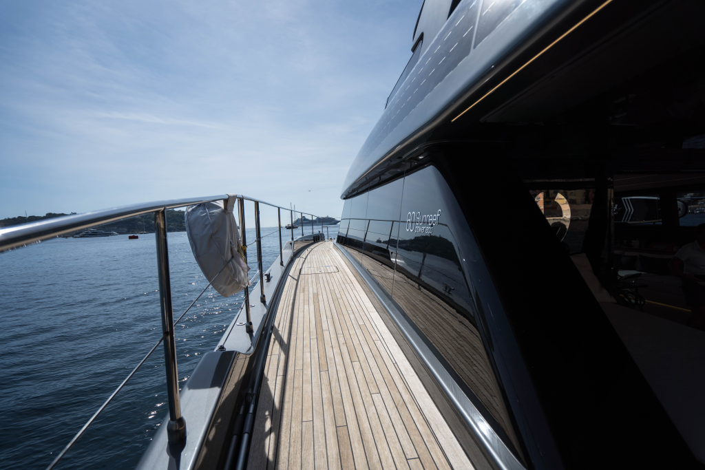 A view from the deck of a Sunreef Yachts vessel, showcasing sleek lines and polished railings with a calm sea in the background.