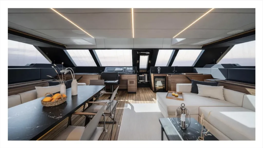 Widok wnętrza luksusowego katamaranu Sunreef Yachts ukazujący przestronną część salonową o nowoczesnym wzornictwie, wyposażoną w kuchnię, sofę i stół jadalny.