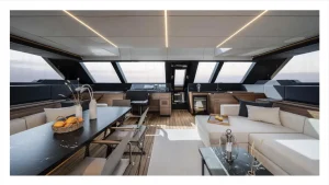 Widok wnętrza luksusowego katamaranu Sunreef Yachts ukazujący przestronną część salonową o nowoczesnym wzornictwie, wyposażoną w kuchnię, sofę i stół jadalny.