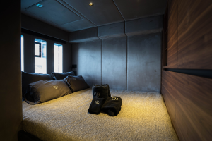 A cozy bedroom inside a yacht by Sunreef Yachts, featuring a gray bed with dark pillows and soft towels placed neatly.
