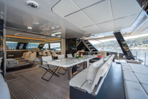 The image shows the luxurious interior of a Sunreef Yachts catamaran. The spacious dining area features a large table with comfortable seating. The design is modern, with sleek lines and ample lighting. Large windows offer a stunning view of the water.