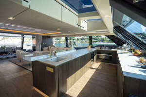 Interior of a luxury yacht from Sunreef Yachts, featuring a spacious kitchen with a large island, modern appliances, and a panoramic view through large windows.