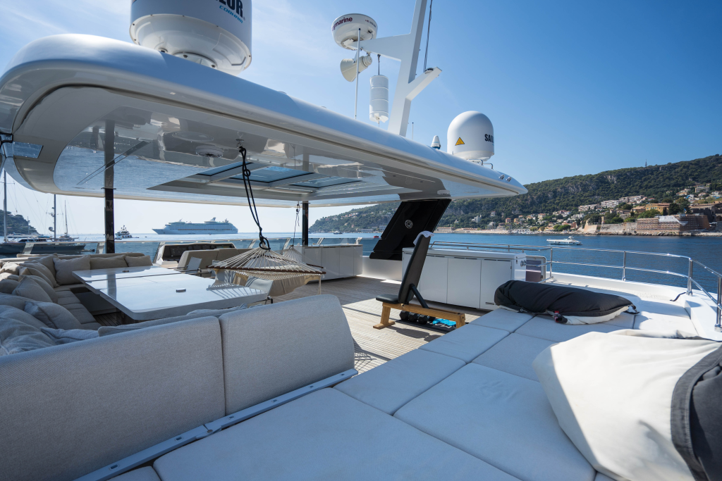A luxurious Sunreef Yachts deck with sun loungers and seating area overlooking a scenic coastal view.