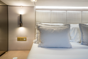 Interior of a Sunreef Yachts bedroom with luxurious decor, featuring an elegant bed with plush pillows and soft lighting.