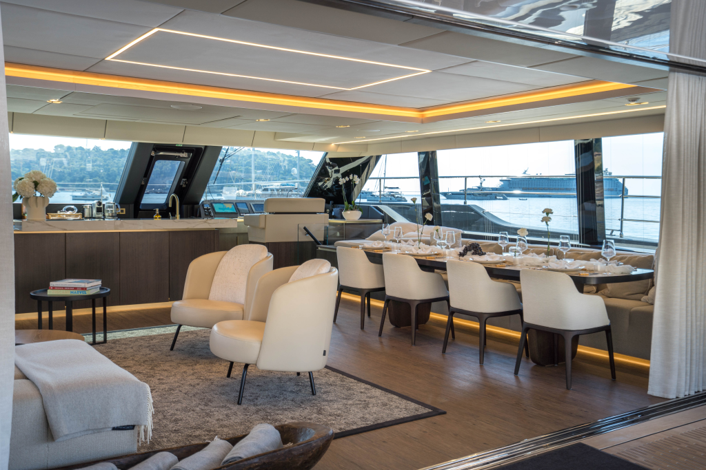 Interior of a luxury Sunreef Yachts vessel, featuring a modern dining area with a set table, elegant lighting, and comfortable seating. Large windows provide a view of the water.