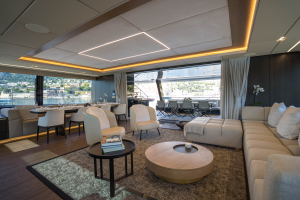 The interior of a luxurious Sunreef Yachts vessel, featuring a spacious lounge area with modern furnishings, large windows offering a scenic view, and elegant lighting details.