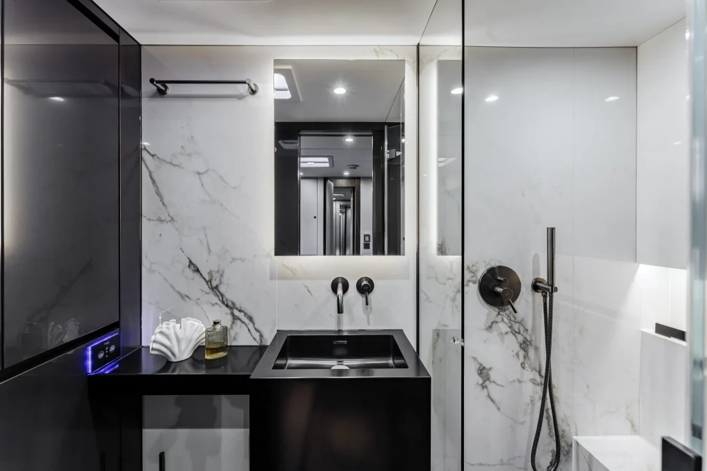 Luxurious and modern bathroom interior featuring marble walls, a black sink, and elegant fixtures aboard Sunreef Yachts.