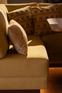 Na zdjęciu eleganckie wnętrze jachtu Sunreef Yachts. Żółta sofa z wzorzystymi poduszkami tworzy ciepłą i przytulną atmosferę.