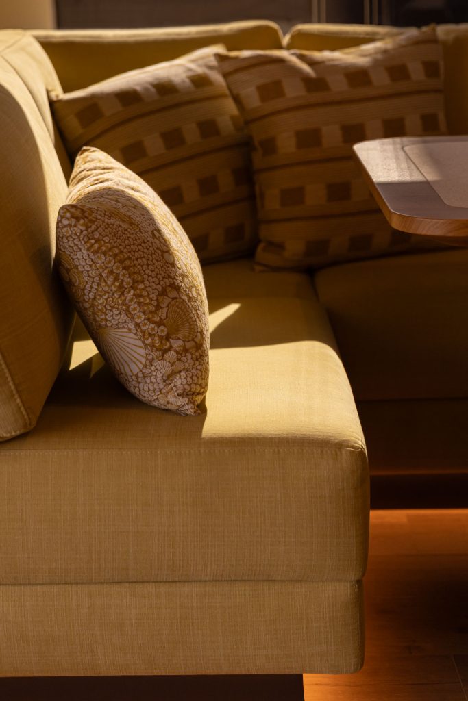 Na zdjęciu eleganckie wnętrze jachtu Sunreef Yachts. Żółta sofa z wzorzystymi poduszkami tworzy ciepłą i przytulną atmosferę.