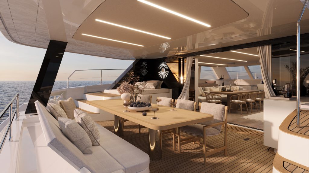 The image shows a luxurious yacht interior by Sunreef Yachts. It features an elegant dining area with a wooden table set for a meal, comfortable seating, and large windows providing a view of the ocean.