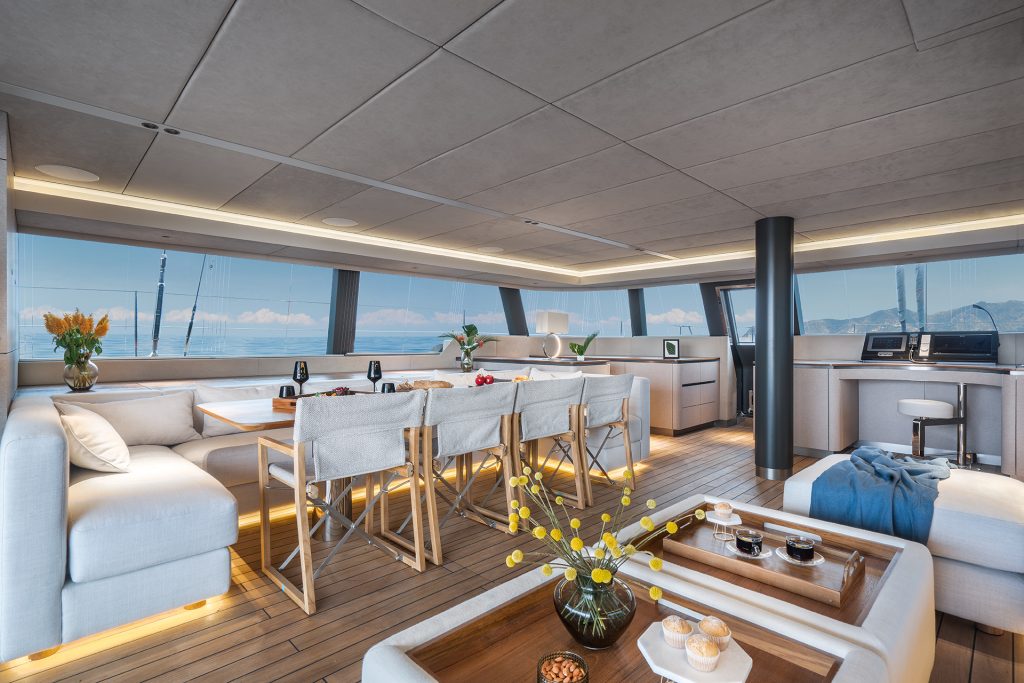 A luxurious interior of a Sunreef Yachts catamaran featuring elegant seating, a dining area, and panoramic windows with a sea view.