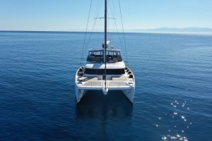 A Sunreef Yachts catamaran sails on a calm sea with a clear blue sky in the background.