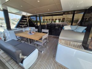 A luxurious deck area on a Sunreef Yachts vessel, featuring a wooden dining table with chairs, cushioned seating, and an elegant, spacious design.