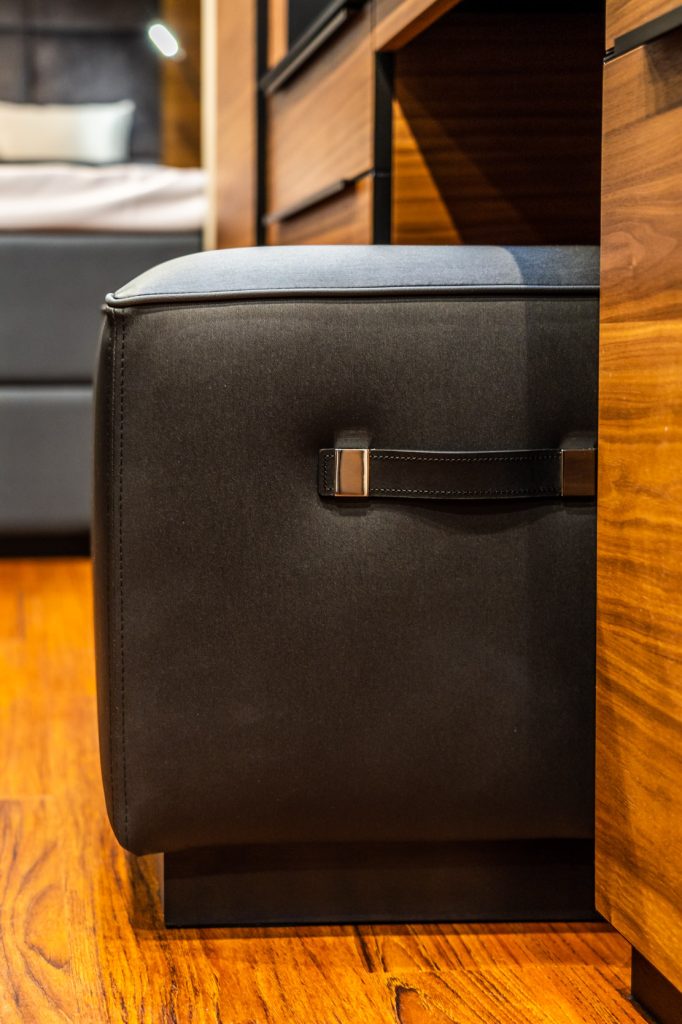 Close-up of a modern interior with wooden furniture and a sleek black leather ottoman, part of the luxurious design of Sunreef Yachts.