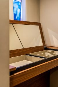 An interior view of a Sunreef Yachts vessel showcasing a wooden vanity with an open mirror and compartmentalized storage.