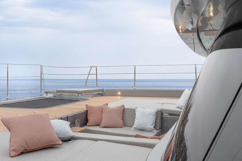 Sunreef Yachts: A modern yacht deck with beige loungers and colorful cushions overlooks a calm sea.