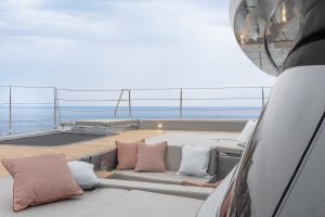 Sunreef Yachts: A modern yacht deck with beige loungers and colorful cushions overlooks a calm sea.