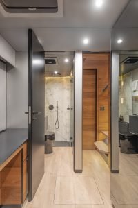 Interior of a luxury bathroom on a Sunreef Yachts vessel, featuring a sleek design with marble accents, wooden flooring, and modern fixtures.