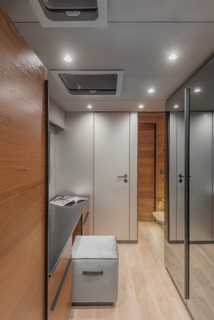 The interior of a luxury yacht by Sunreef Yachts, featuring sleek wooden panels, a modern workstation with a stool, and glossy cabinets. The space is well-lit with recessed lighting.