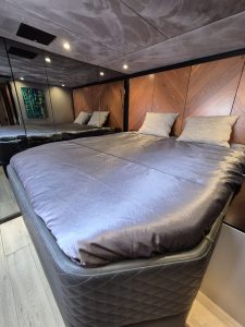 The bedroom inside a Sunreef Yachts vessel features a large, comfortable bed with a sleek design, wooden accent walls, and ambient lighting.