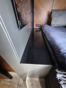 Interior view of a luxury yacht cabin by Sunreef Yachts, featuring a sleek black countertop and a comfortable bed with modern decor.