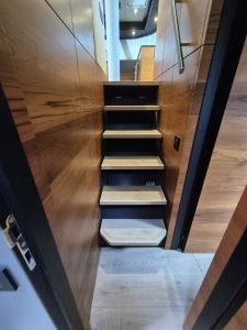 The image shows a staircase inside a Sunreef Yachts boat, featuring wooden steps and walls.