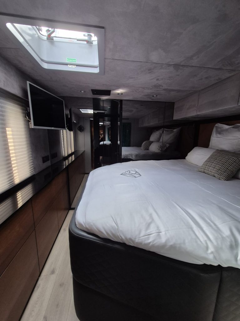 Interior of a Sunreef Yachts cabin with a plush bed, modern furnishings, TV, and overhead skylight.