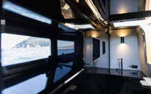Interior of a Sunreef Yachts vessel showing a sleek, modern design with glossy black surfaces, windows revealing a scenic sea view.