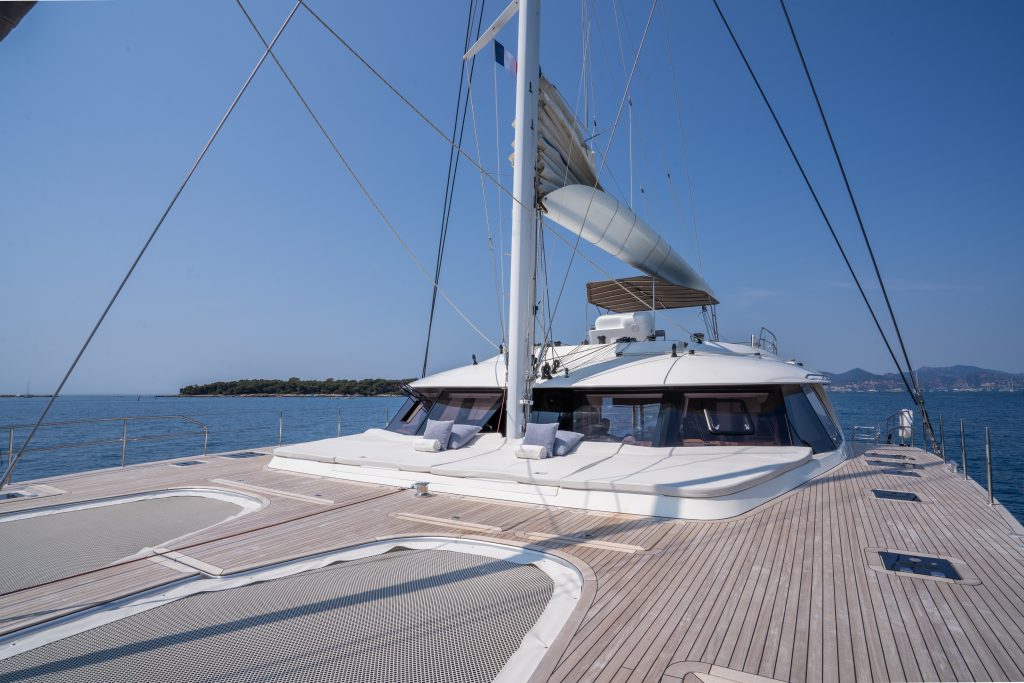 A luxury Sunreef Yachts catamaran with spacious wooden decking and sleek design, sailing on calm blue waters.