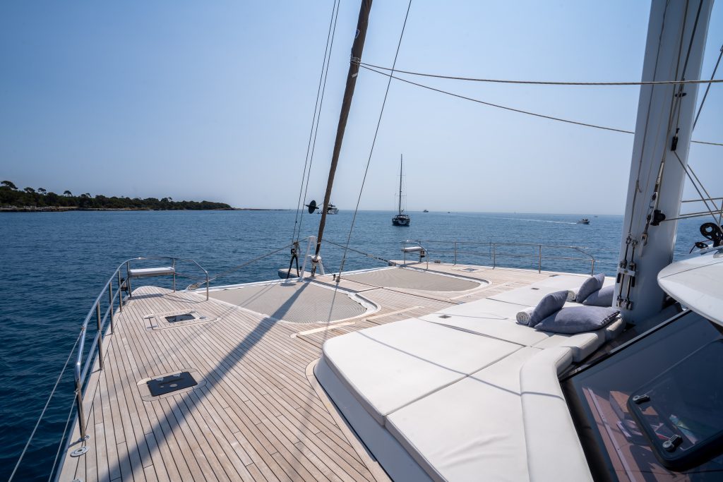 A luxurious Sunreef Yachts catamaran deck with sunbeds and a view of calm blue waters.