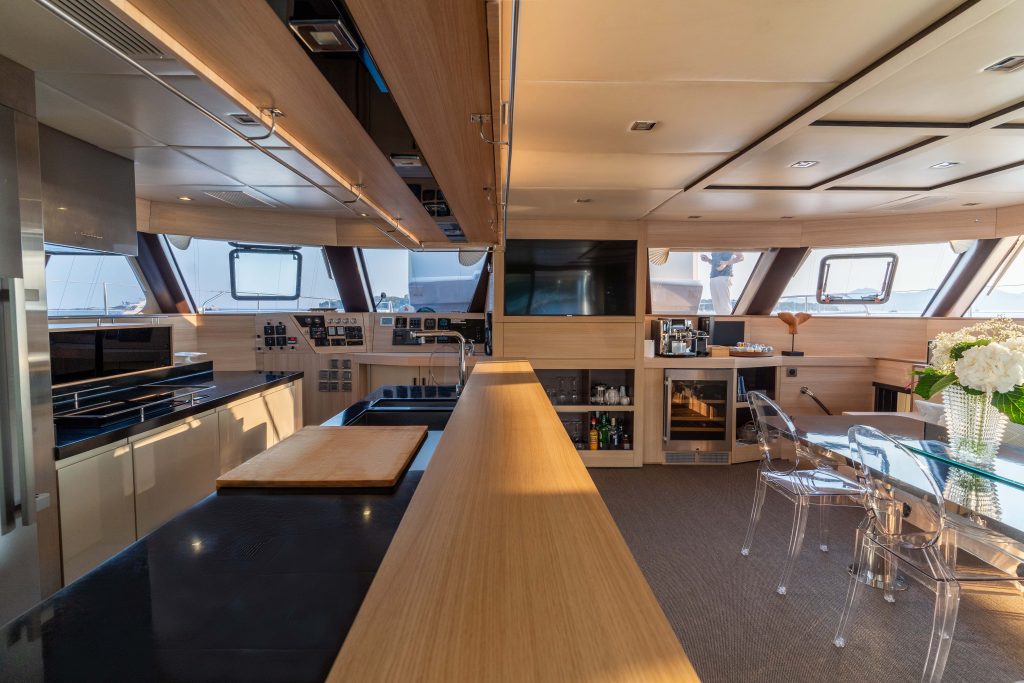 Interior of a luxurious Sunreef Yachts catamaran featuring spacious kitchen and dining area with modern amenities and large windows.