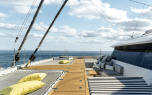 The deck of a Sunreef Yachts catamaran features striped lounging areas with cushions and hammocks with yellow pillows against a backdrop of a blue sea and sky.