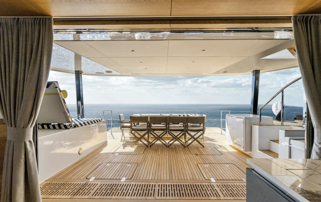 View from the interior of a luxurious Sunreef Yachts catamaran, showing an elegant wooden deck with seating and a stunning ocean view.