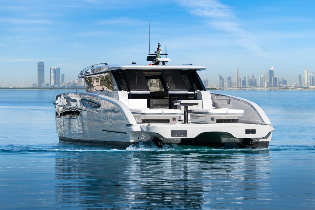 A sleek Sunreef Yachts catamaran on the water with a city skyline in the background, under a clear blue sky.