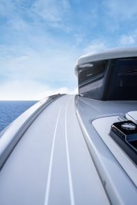 A sleek Sunreef Yachts vessel cruising on the open sea with a clear blue sky overhead.