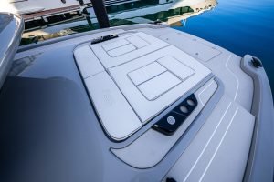 The image shows the deck of a luxury yacht by Sunreef Yachts, featuring sleek, cushioned sunbathing areas and a modern design near the water.