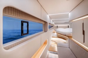 The interior of a Sunreef Yachts cabin with a panoramic view of the ocean, featuring sleek modern design elements, a bed, and a sofa.
