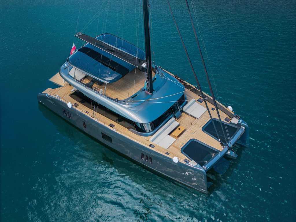 A luxurious Sunreef Yachts catamaran with a sleek design is sailing on clear blue waters.