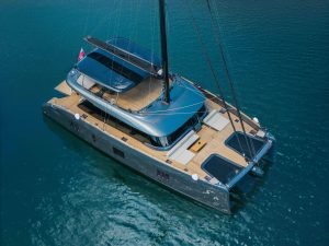 A luxurious Sunreef Yachts catamaran with a sleek design is sailing on clear blue waters.