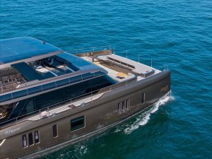A Sunreef Yachts catamaran with sleek design sails on clear blue water, featuring spacious deck and modern amenities, with solar panels visible.