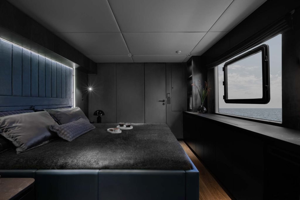 A luxurious bedroom inside a Sunreef Yachts vessel with a large bed, elegant decor, and a sea view through a window.